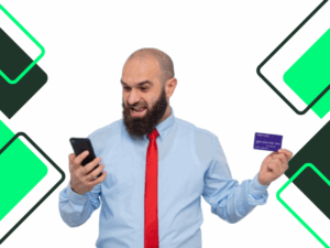 uso de tarjetas de crédito: Hombre barbudo con corbata roja y camisa azul sosteniendo una tarjeta de crédito y un teléfono inteligente, mirándolo feliz y emocionado, sonriendo alegremente.