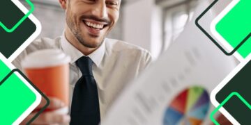reduce your business costs: happy-young-manager-examining-business-progress-while-reading-charts-and-drinking-coffee-in-office